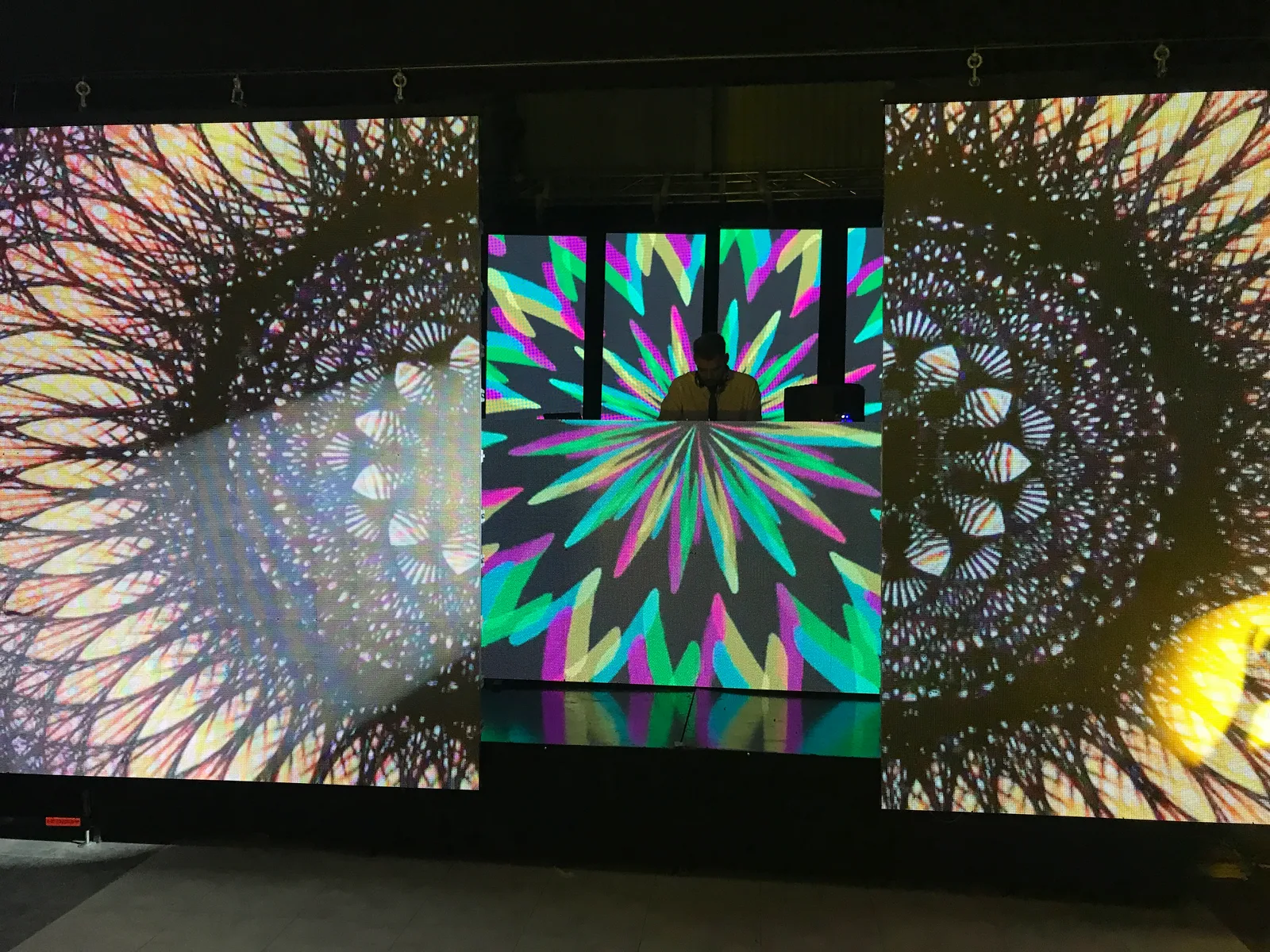 Paneles LED con figuras multicolores y visuales circulares a ambos lados.