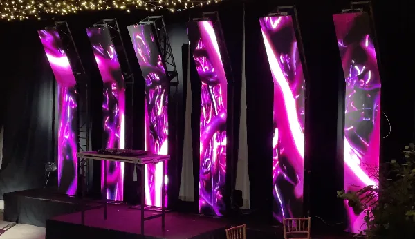 Paneles LED inclinados con visuales violetas detrás de la mesa del DJ.