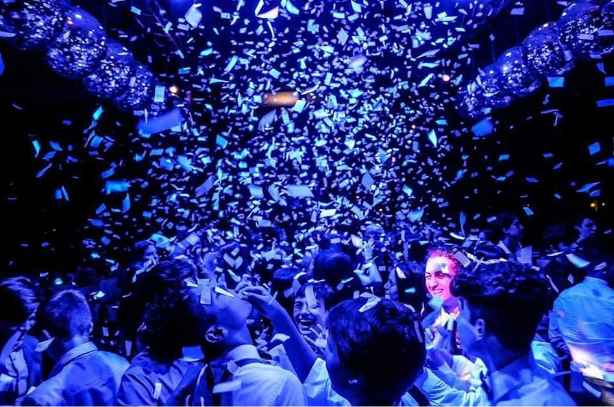 Papelitos blancos en el aire sobre una pista con invitados.