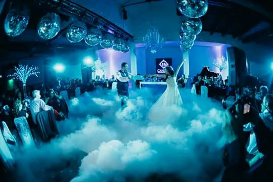 Novia en una pista cubierta de humo bajo con invitados alrededor.
