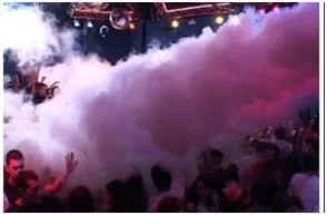 Chorro de nube blanca en un evento con luces violetas.