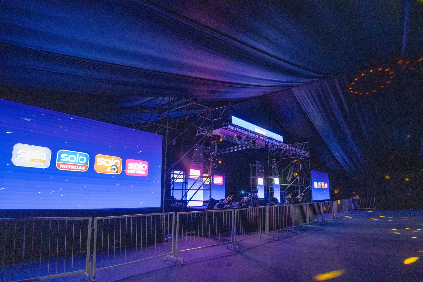Escenario con cubierta estructural junto a una pantalla con logos.