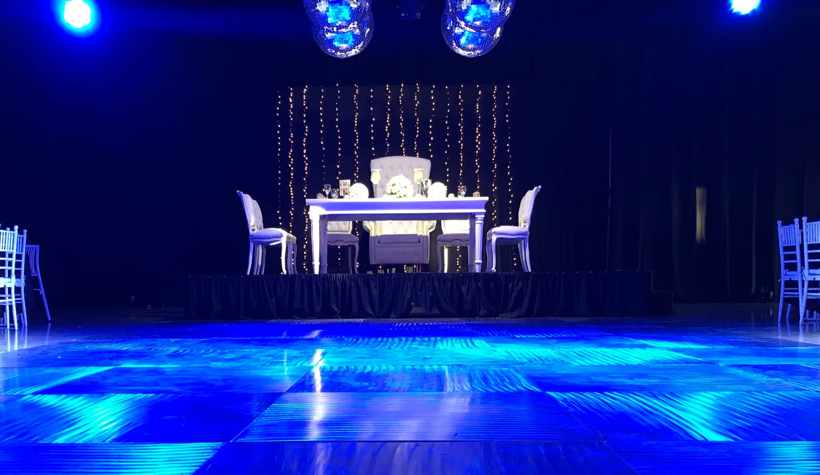 Mesa principal elevada sobre una tarima con iluminación azul.