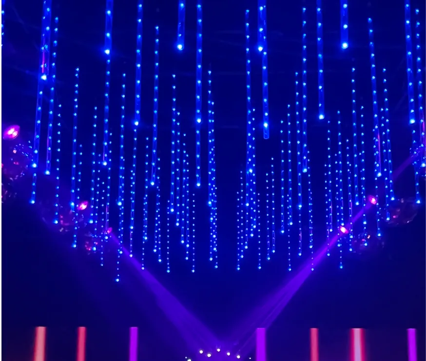 Líneas de puntos LED azules suspendidas sobre luces violetas.